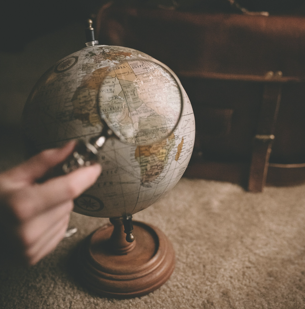 Photo of a magnifying glass held over a globe