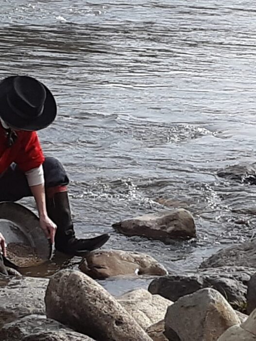 a person in boots and hat cleaning rocks in water