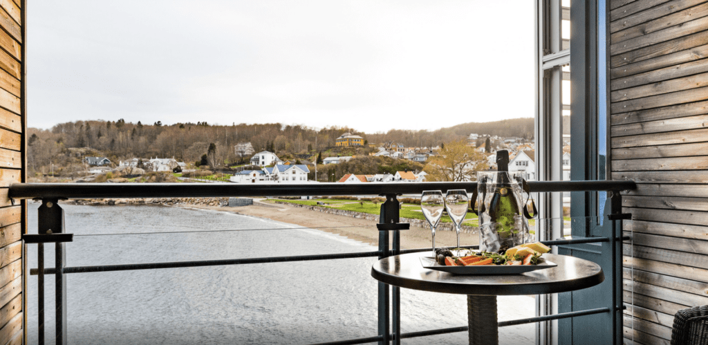 a table with food and wine glasses on it overlooking a body of water