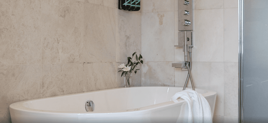 a white bathtub with a white towel and a plant in a vase