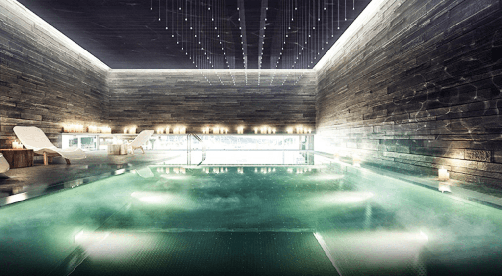 a pool with lights and a wood wall