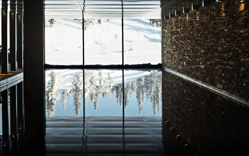 a room with a large window and a snowy mountain and trees