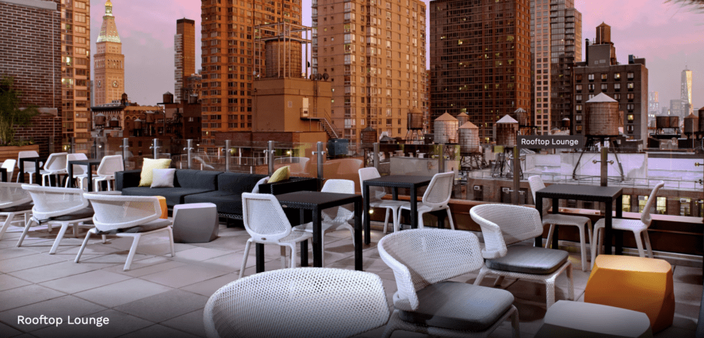 a rooftop patio with chairs and tables and a large city skyline